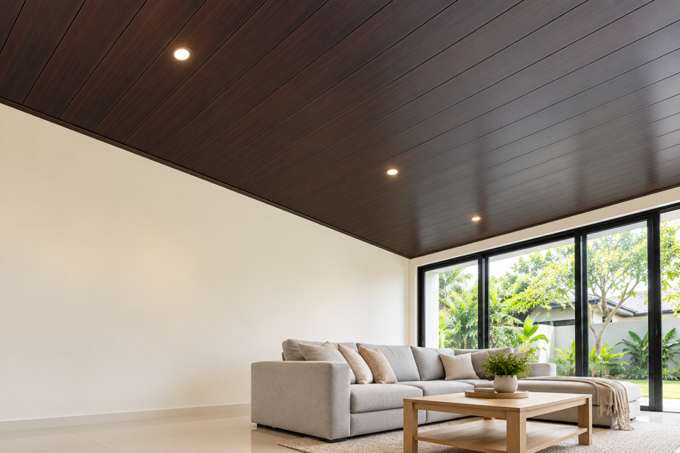 Illustration of a deep Walnut woodgrain PVC ceiling in a living room with large sliding doors to the garden
